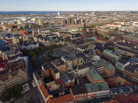 Aerial view of the historic Stortorget square framed by colorful buildings and the imposing St. Peter's Church under a vast sky, Malmo, Sweden.