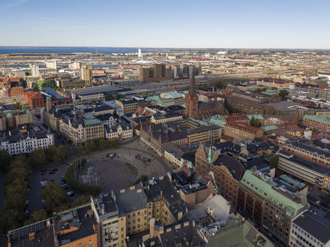 Aerial view of Stortorget square and the spire of St. Peter's Church cutting through the skyline amidst a tapestry of red-tiled roofs, Malmo, Sweden.