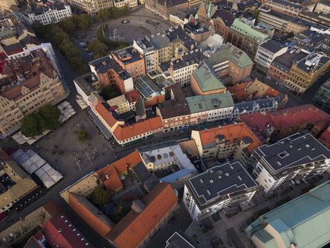 Aerial view of the vibrant Lilla Torg square, where historic buildings with terracotta roofs meet modern architecture under a soft, fading sunlight, Malmo, Sweden.