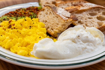 brunch dish with avocado, egg scramble, bread and yogurt