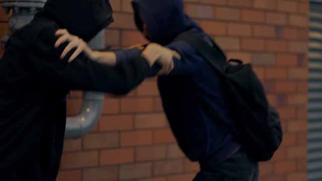 Young street gang fight between two boys in hoodies at night urban alley