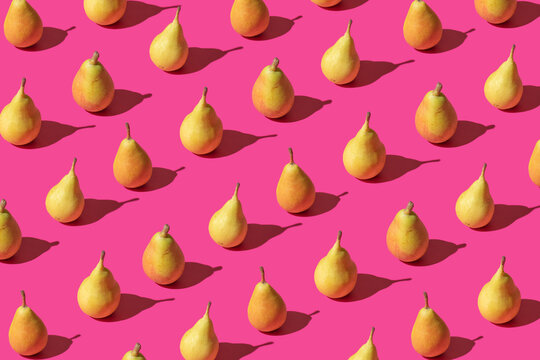 Creative pattern made with fresh pears against pastel pink backround.Minimal summer fruit layot.
