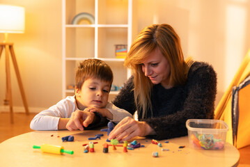 Fototapeta premium Childminder and boy playing with modeling clay at home