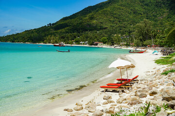 Relaxing beach scene with beach umbrella shading comfortable beds , cabana, water, sunshade. Beautiful beach and white sand with beach chair. Asian tropical beach paradise in Thailand