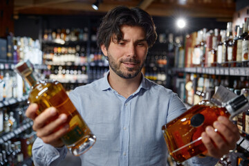A man holds two bottles of alcohol in a liquor store