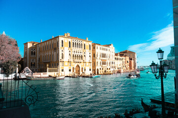 Historic Venetian palazzo on the waterfront, with reflections on calm blue water below.
