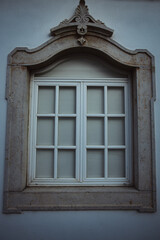 Close-up view of an elegant white window framed by ornately carved stone on a historic European building.