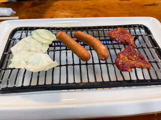 ウインナーと牛ロース肉を焼いてる。焼肉のお店。風景。