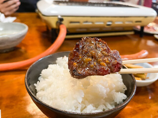 焼いたお肉を味噌タレに付けてご飯と一緒に食べる。焼肉屋の風景。