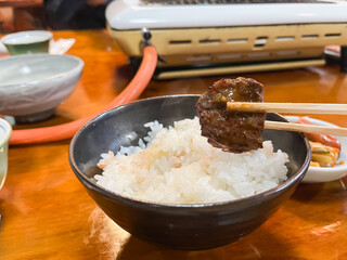 焼いたお肉を味噌タレに付けてご飯と一緒に食べる。焼肉屋の風景。