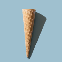 Sunny ice cream cone with shadow on pastel blue backround.Minimal summer concept.Flat lay
