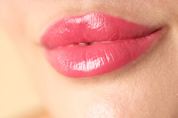 Fototapeta premium Woman with beautiful pink lipstick on her lips against beige background, macro view