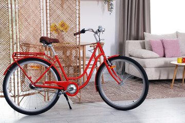 Stylish red bicycle near folding screen indoors