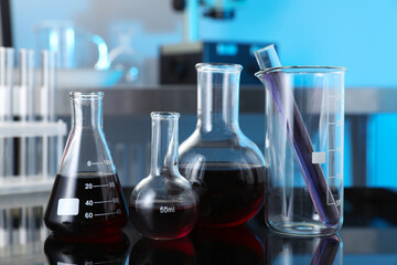 Different glassware with red liquid on table in laboratory, closeup