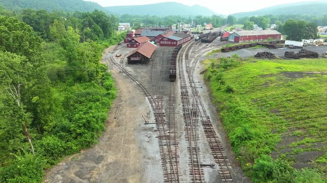 A visit to an old railway yard surrounded by green hills and rustic buildings. The area features tracks winding through the landscape, showcasing remnants of past train activity.