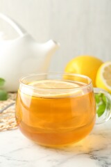 Aromatic tea in cup with lemon on white marble table, closeup