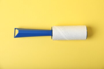 One lint roller on yellow background, top view