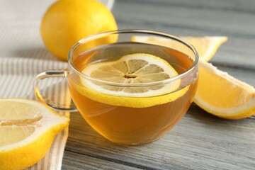 Aromatic tea in cup and lemons on wooden table, closeup