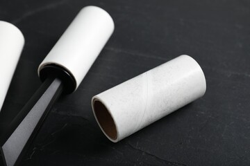 Lint roller and adhesive rolls on black table, closeup