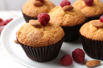 Fresh muffins with raspberries and almonds on table, closeup