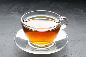 Aromatic tea in glass cup on black table, closeup