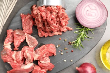 Making minced meat with grinder and spices on grey table, top view