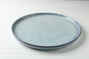 Stylish ceramic plate on white wooden table, closeup