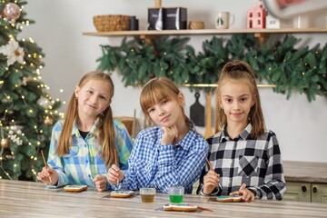 Three girls decorating Christmas cookies at festive kitchen table