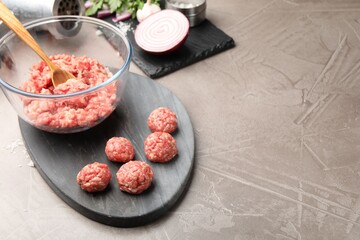 Raw meatballs, minced meat, parsley and onion on grey table. Space for text