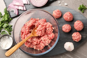 Raw meatballs, ground meat, parsley, salt and onion on grey table, flat lay