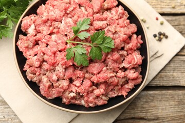 Raw minced meat with parsley and spices on wooden table, flat lay