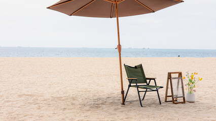 Minimal beach setup with chair and umbrella on sandy shore for summer relaxation