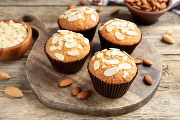 Tasty muffins with almond flakes and nuts on wooden table, closeup