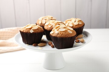 Tasty muffins with almond flakes and nuts on white wooden table, closeup