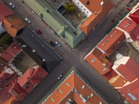 Aerial view of terracotta rooftops meeting at sharp street corners, creating geometric patterns contrasting with the occasional green roof, Kalmar, Kalmar County, Sweden.