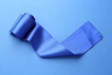 Beautiful ribbon on blue background, top view