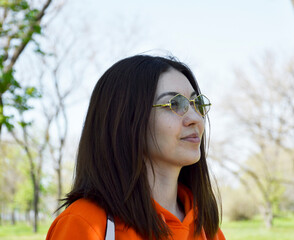 A beautiful woman with a bob haircut and sunglasses takes a walk in a city park. Strolling in the fresh air. The beautiful girl poses. Slanted eyes.