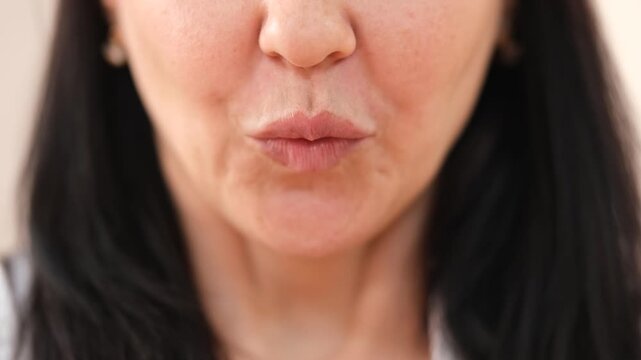 Close-up of a woman's mouth as she actively speaks, gossips, and smiles, showcasing various facial expressions and emotions. Her lips move dynamically, conveying a lively and engaging conversation