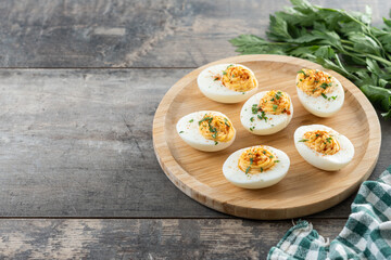 Homemade hard Boiled Deviled Eggs garnished with herbs on wooden table. Copy space