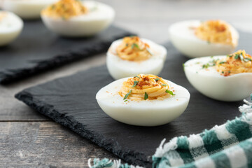 Homemade hard Boiled Deviled Eggs garnished with herbs on wooden table