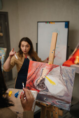 An artist explains how light falls on an object in an art class. Education and learning concept. People drawing with brush on easel. Girl mixing and combining colors. Woman painting in a workshop.