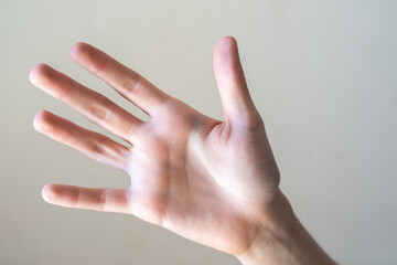 A close-up of a human hand with fingers extended, palm facing forward. The hand is light-skinned with visible details of the fingers and palm.