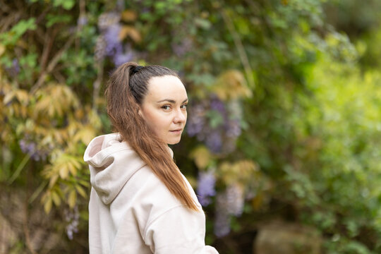 Young woman looking back in green garden - Powered by Adobe