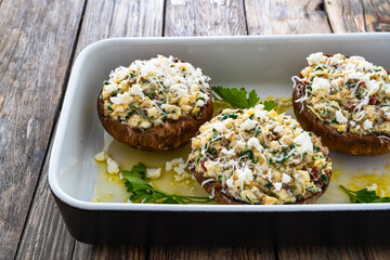 Stuffed portobello mushrooms in baking dish ready for baking on wooden table