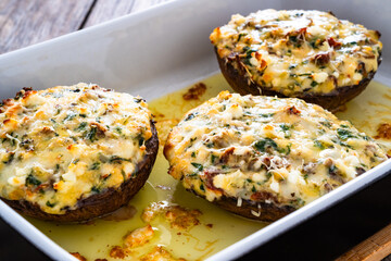 Stuffed portobello mushrooms in baking dish on wooden table