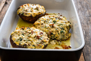 Stuffed portobello mushrooms in baking dish on wooden table