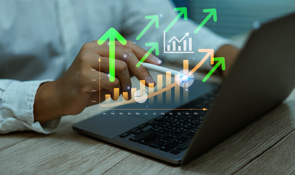 Businessman analyzing growth chart with green arrows and increasing statistics on laptop, symbolizing financial success, data-driven decision making, business growth performance