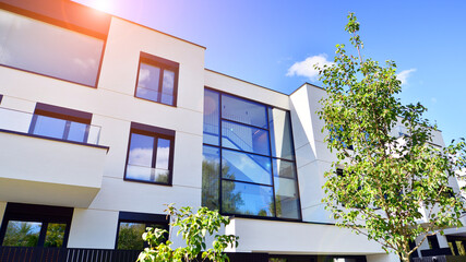 Modern apartment building with balconies and greenery. The structure features a glass wall and lush plants in front, showcasing contemporary architecture.