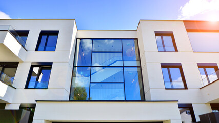 Modern luxury apartment building with balconies.The structure features a glass wall in front, showcasing contemporary architecture.