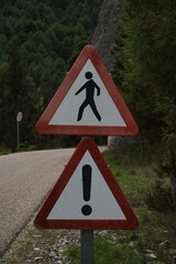 The upper triangular traffic sign warns pedestrians, and the lower sign is a general hazard warning.